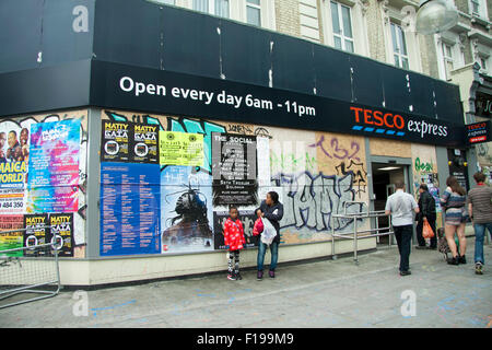 Notting Hill, London, UK. 30. August 2015. Käufer außerhalb einer verschalten Tesco-Supermarkt in Ladbroke Grove. Der Notting Hill Carnival, Europas größte Straßenfest startet der offizielle Startschuss für die zweitägige Karneval in Notting Hill mit großen Polizeipräsenz zu markieren Stockfoto