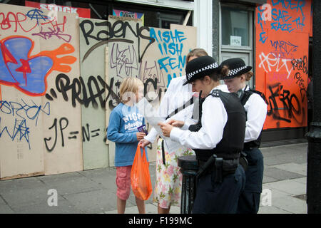 Notting Hill, London, UK. 30. August 2015. Polizisten helfen Nachtschwärmer mit Anfahrtskizze als dem Notting Hill Carnival, Europas größte Straßenfest startet der offizielle Startschuss für die zweitägige Karneval in Notting Hill mit großen Polizeipräsenz zu markieren Stockfoto