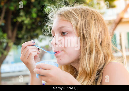 Blonde kaukasische Teenager-Mädchen isst gefrorenen Joghurt, Nahaufnahme outdoor Portrait mit Tageslicht Stockfoto