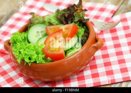 Grüner Salat in Ton Schüssel auf karierte Serviette Stockfoto