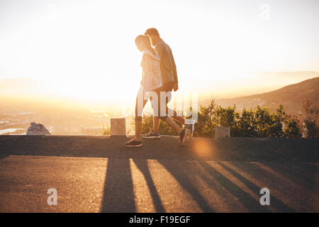 Paar Fuß entlang der Straße bei Sonnenaufgang. Paar einen Spaziergang am Hang Road mit hellem Sonnenlicht zu sprechen. Stockfoto