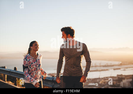 Bild des Fit junger Mann und Frau Joggen auf Landstraße, betrachten einander. Läufer genießen Morgenlauf. Stockfoto