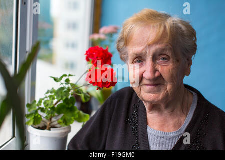 Porträt der älteren Frau stand auf dem Balkon unter den Blumen. Stockfoto