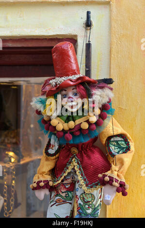 Eine bunte Clown-Marionette hängen Fäden vor einem Schaufenster in Santorini, Griechenland. Stockfoto