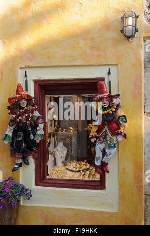 Zwei bunte Clown-Puppen hängen Fäden vor einem Schaufenster in Santorini, Griechenland. Stockfoto