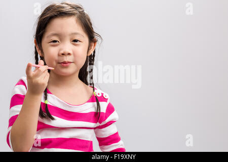 Glückliche kleine Mädchen essen Snack auf weißem Hintergrund. Stockfoto