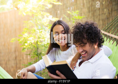 Glückliches Paar Lesebuch auf Hängematte im freien Stockfoto