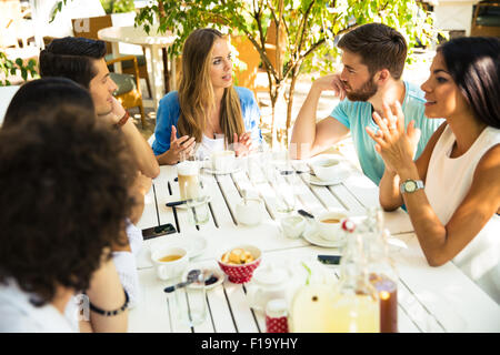 Lächelnde junge Freunde genießen Mahlzeit im Restaurant unter freiem Himmel Stockfoto