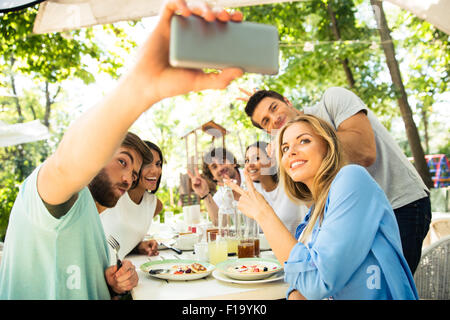 Porträt einer fröhlichen Freunde machen Selfie Foto auf Smartphone im Restaurant unter freiem Himmel Stockfoto