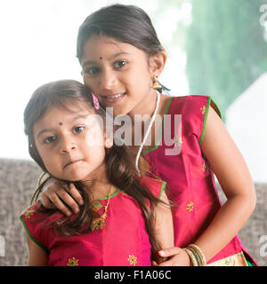 Indische Mädchen ihre jüngere Schwester mit Liebe zu umarmen. Asiatische Kinder zu Hause. Schöne Töchter im traditionellen Indien Sari. Stockfoto