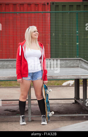 Mädchen im Teenageralter stehend mit Skateboard in einem Skatepark. Stockfoto