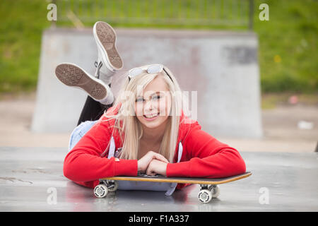 Ziemlich junges Mädchen hinlegen auf den Bauch außerhalb in einem Skatepark. Stockfoto