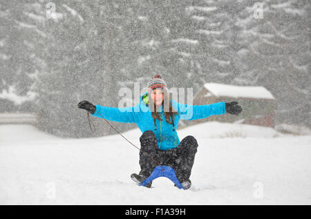 Mädchen auf Schlitten bergab im Winter Stockfoto