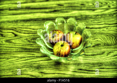 Äpfel in einem Glas Schüssel auf einem Holztisch, als ein HDR-Bild verarbeitet. Stockfoto