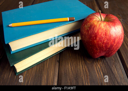 Alte Bücher und roter Apfel auf hölzernen Hintergrund mit Textfreiraum Stockfoto