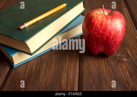 Alte Bücher und roter Apfel auf hölzernen Hintergrund mit Textfreiraum Stockfoto