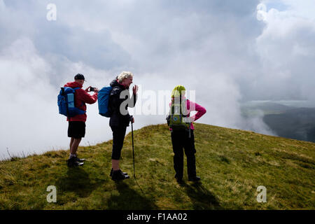 Drei Wanderer Wandern auf Trum Ddysgl Berg nach Westen entlang Nantlle Kante mit niedrigen Wolken in Berge von Snowdonia, Wales, UK Stockfoto