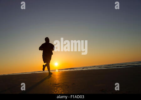 Über Gewicht Läufer laufen am Strand bei Sonnenaufgang Stockfoto