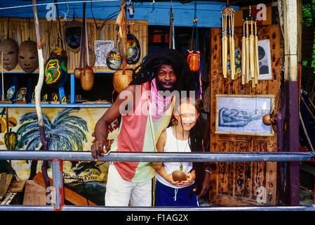 Kaukasische Mädchen posiert für ein Foto mit einem lokalen Grenadian Handwerker vor seinem Geschäft in Grenada. Karibik Stockfoto