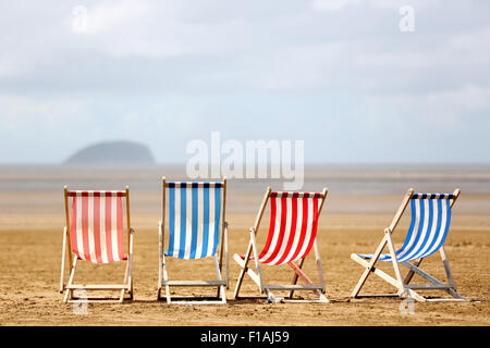 Eine Reihe von gestreiften leer Traditionelle seaside Liegestühle warten auf Kunden an einem warmen sonnigen Tag am Strand in ein englisches Seebad Stockfoto