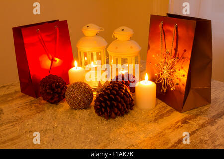 Weihnachten-Ambiente mit Kerzen, Tannenzapfen, Einkaufstaschen und Kugeln. Stockfoto