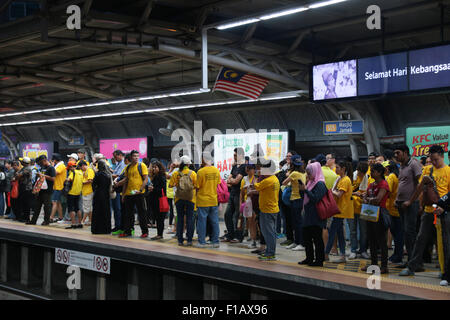 KUALA LUMPUR, MALAYSIA, 29. August 2015: gelbes Hemd BERSIH Rallye Besucher warten auf ihre Fahrt im Bahnhof Bahnsteig Masjid Jamek Stockfoto