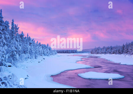 Eine schnelle in einem Fluss im Winter bei Sonnenaufgang. Fotografiert an der Äijäkoski-Stromschnellen im Fluss Muonionjoki im finnischen Lappland. Stockfoto