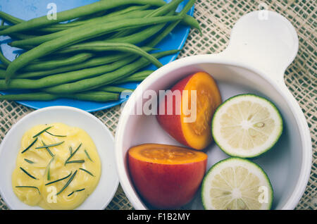 bunte Teller mit grünen Bohnen, Butter und Schüssel mit Baum Tomate und Limetten Stockfoto