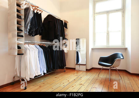 Kleiderschrank im Zimmer mit einem großen Fenster, einen schwarzen Stuhl und einen Spiegel Beleuchtung Stockfoto