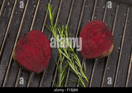 Reife aromatische rote Beete schneiden in der Mitte und Rosmarin Zweig auf Metallgitter liegend Stockfoto