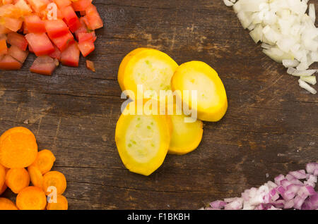 frische reife Zucchini, Karotten, Tomaten und Zwiebel gehackt auf einem Holzbrett Stockfoto