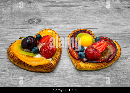 Obstkuchen in Herzform auf grauem Hintergrund aus Holz. Stockfoto