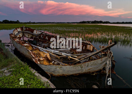 Ein zerstörten Boot entlang der Marsch bei Sonnenuntergang Folly Beach, SC Stockfoto