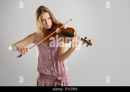 Hübsche junge Geigerin im stilvollen rosa Outfit stehen Geige zu spielen, wie sie ein klassisches Konzert in der Fortbildungsangebote gibt Stockfoto