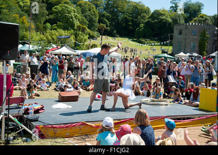 Familien beobachten einen akrobatischen Akt in der Sommersonne von Garküchen und Zelten am Hafen Eliot Festival Cornwall Stockfoto