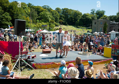 Familien beobachten einen akrobatischen Akt in der Sommersonne von Garküchen und Zelten am Hafen Eliot Festival Cornwall Stockfoto