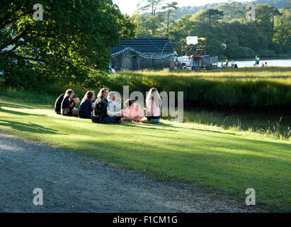 Festivalbesucher zu sitzen, entspannen und trinken im Schatten am Flussufer der Mündung am Hafen Eliot Festival Cornwall Stockfoto