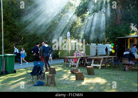 Festivalbesucher trinken im Schatten mit der Sonne, durch Rauch am Hafen Eliot Festival Cornwall Stockfoto