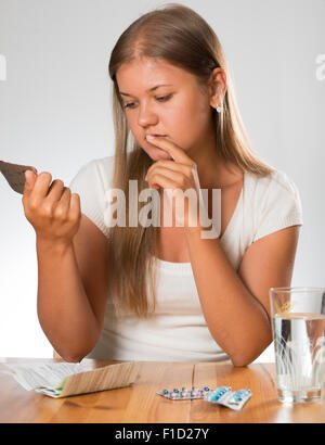 Junge Frau auf dem weißen Hintergrund hält in Händen Medikamente und verschreibungspflichtige lesen Stockfoto