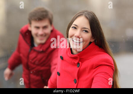 Glückliches Paar rote Jacke läuft auf Kamera im Winter tragen Stockfoto