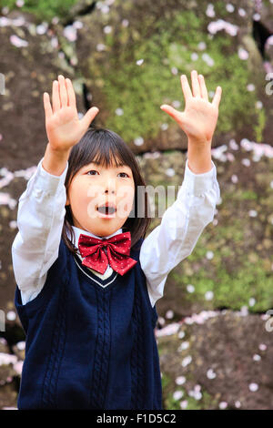 Japanische Yosakoi Tanz. Schule Mädchen, 9-10 Jahre alt, vor der Mauer zu singen. Close Up, Taille von Mädchen mit erhobenen Armen. Trägt Jumper. Stockfoto