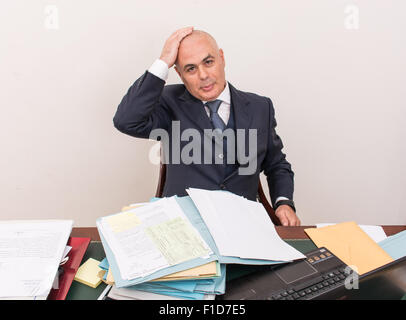 Business-Mann am Schreibtisch, tief in Gedanken, starrte in den Weltraum, konzentrierte sich auf seine Gedanken. Stockfoto