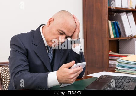 Der Mann am Schreibtisch, betrachten Sie Ihre i Pad/Tablet, in seinem Büro. Stockfoto