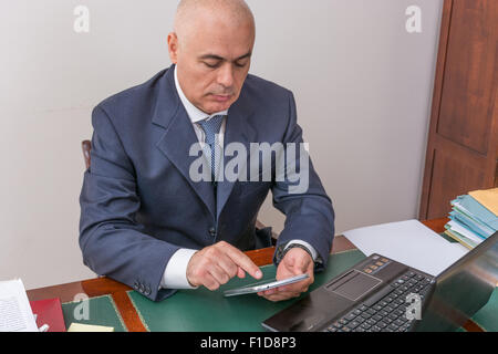 Der Mann am Schreibtisch, betrachten Sie Ihre i Pad/Tablet, in seinem Büro. Stockfoto