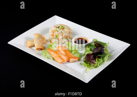 Menü mit Fisch vom Grill mit Reis und Gemüse auf weiße Platte, auf schwarzen backgrpound Stockfoto