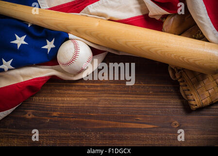 Eine alte, antike amerikanische Flagge mit Vintage Baseball-Ausrüstung auf einer Holzbank Stockfoto