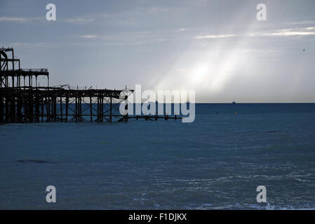 Reste der West Pier und Lichtstrahlen auf ein bewölkter Himmel, Brighton England niedergebrannt. Stockfoto