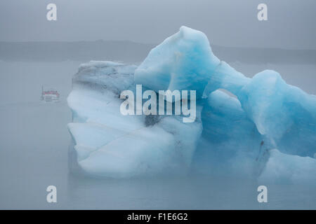 Touristen, die an einem nebligen Sommertag im August in Island eine Bootstour im Nebel zwischen gigantischem Eisberg in der Jokulsarlon Glacial Lagoon Unternehmen Stockfoto