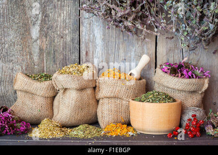 Getrocknete Heilkräuter in Hessischen Taschen und Mörtel auf Holzwand Hintergrund, Kräutermedizin. Stockfoto