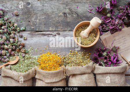 Heilende Kräuter im Hessischen Taschen, hölzerne Mörser und Rezepte, Kräutermedizin. Ansicht von oben. Stockfoto